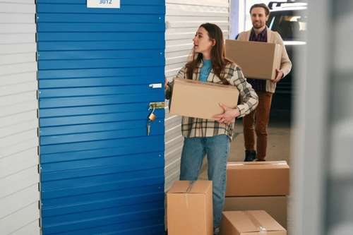 Young woman and man carrying boxes into storage unit