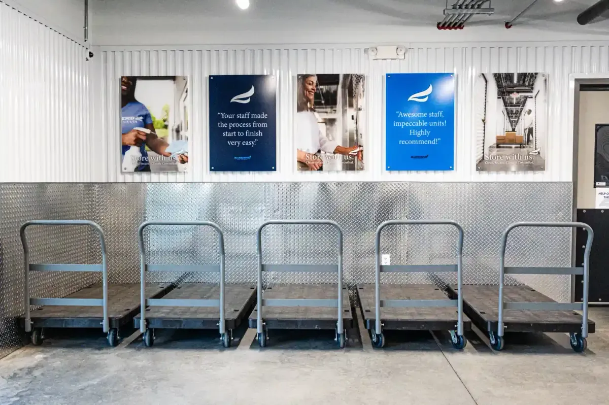 Moving carts lined up below Bluebird Self Storage customer review wall panels