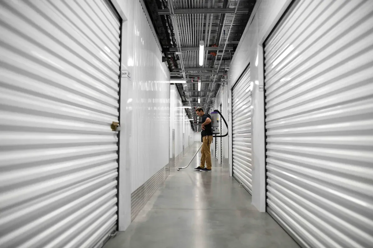 A man cleaning the floors in a hallway of an indoor self storage facility.