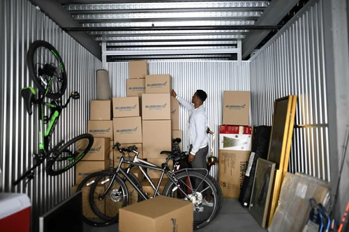 A man checking his brown storage boxes in a unit.