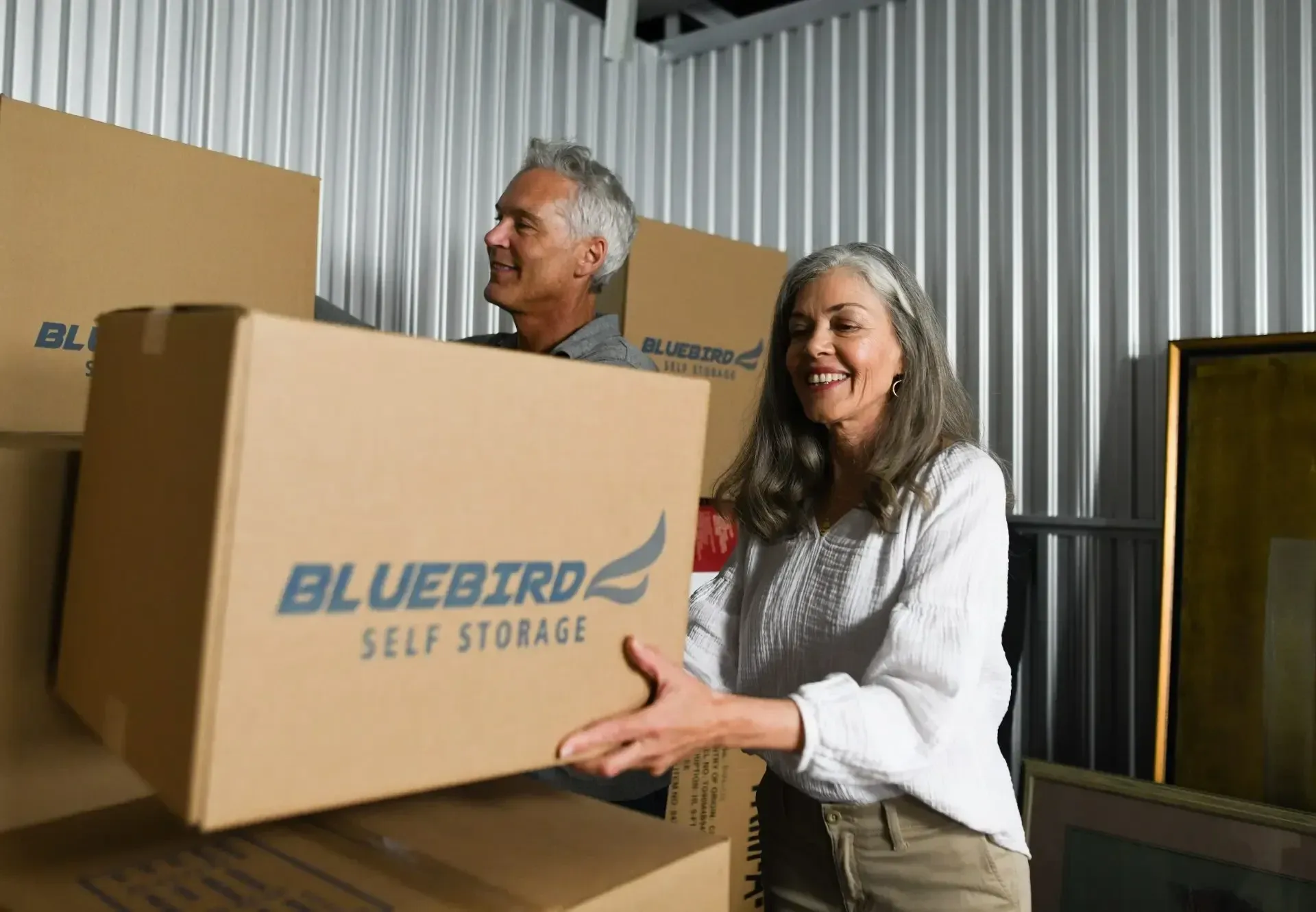 Woman and man rearranging boxes in climate controlled storage unit.